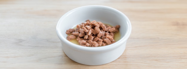 Wet food for cats and dogs in a white bowl on wooden floor