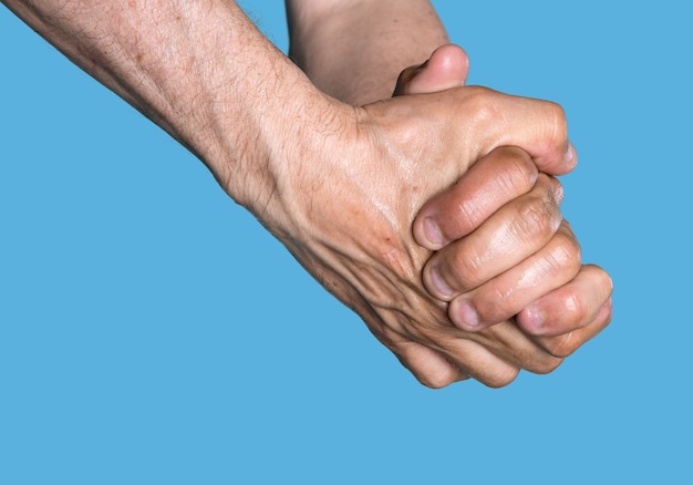 Wet hands of an elderly man isolated on blue