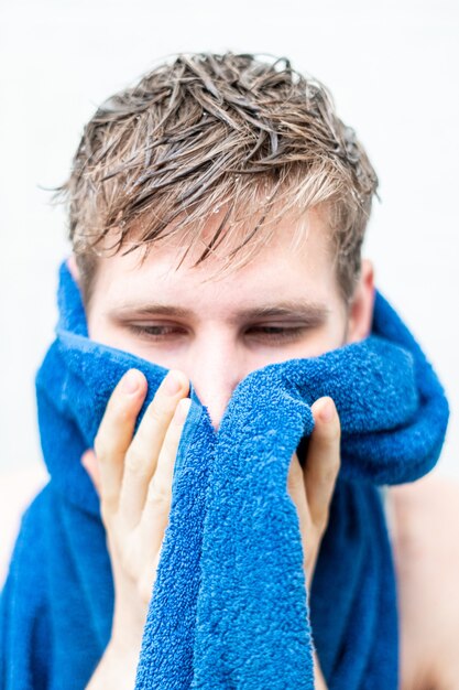 Wet men hair and holding a towel after taking a shower at home