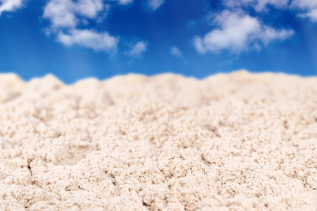 La sabbia bagnata è nitida in primo piano e sfocata in lontananza su uno sfondo di cielo blu