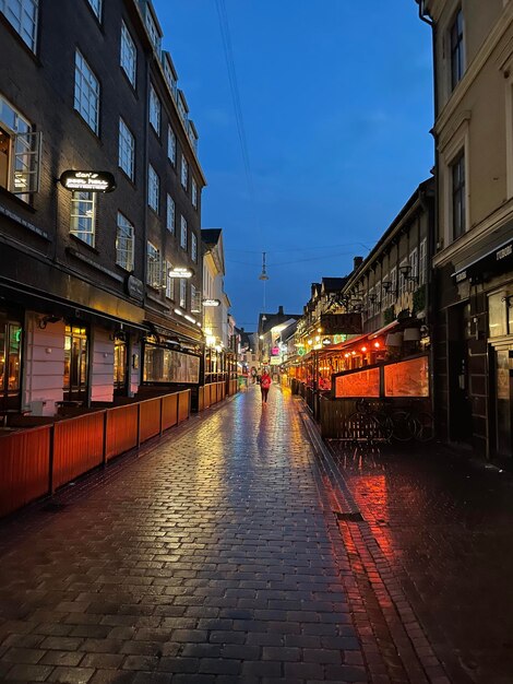 Wet street amidst buildings in city at night