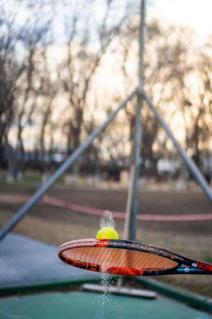 Photo wet tennis ball hit by orange racket on cloudy day