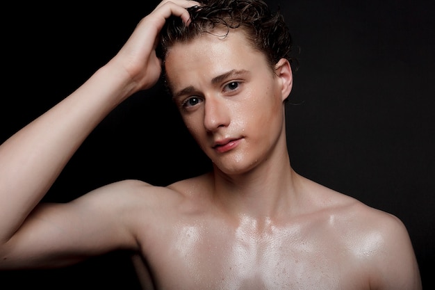 Wet young man with black hair on a black background