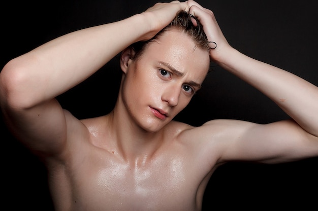 Wet young man with black hair on a black background