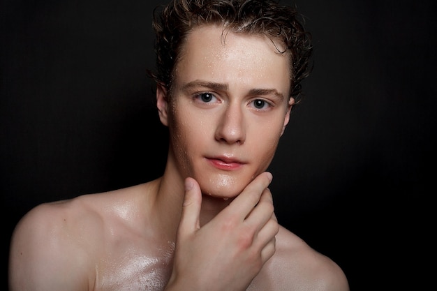 Wet young man with black hair on a black background