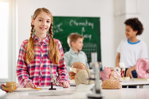 Wetenschap les. Leuke slimme meid die aan de tafel staat terwijl ze een wetenschapsles heeft