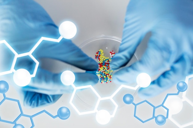 wetenschap, scheikunde, biologie, geneeskunde en mensen concept - close-up van wetenschapper of arts handen vasthouden en gieten pil inhoud in petrischaal in laboratorium met moleculaire structuur