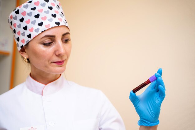 Wetenschap scheikunde biologie geneeskunde en mensen concept jonge vrouwelijke wetenschapper met reageerbuis met bloedmonster maken van onderzoek in klinisch laboratorium close-up