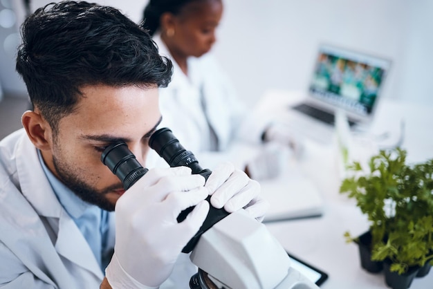 Foto wetenschappelijk onderzoek en mannelijke wetenschapper met een microscoop voor een analysetest of experiment in een medisch laboratorium innovatiebiotechnologie en man farmaceutisch onderzoeker of expert die in een laboratorium werkt