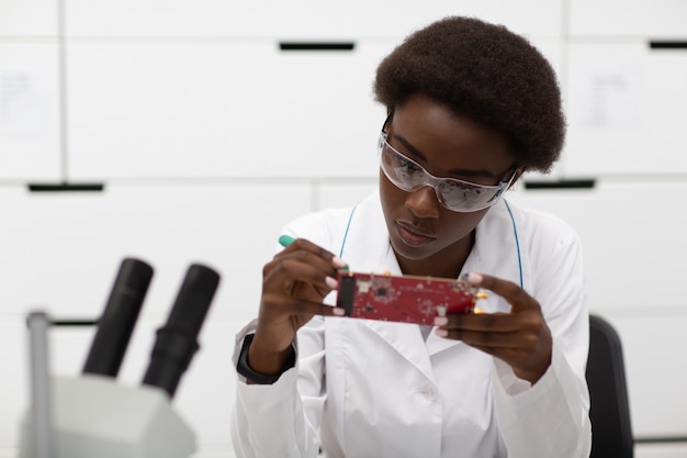 Wetenschapper Afro-Amerikaanse vrouw ingenieur in laboratorium met microscoop
