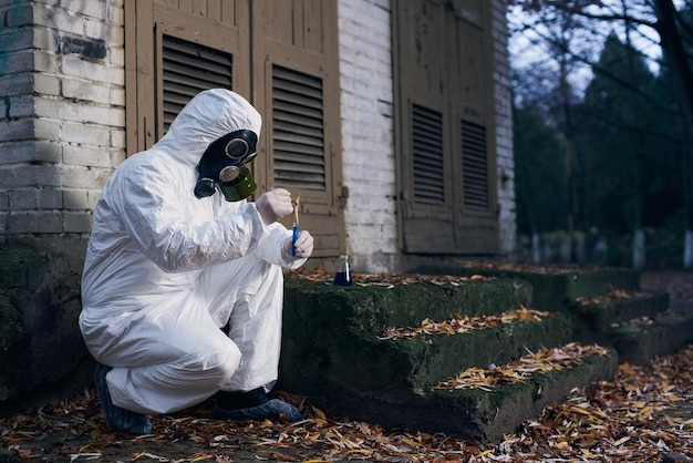 Wetenschapper die buiten onderzoek doet met een witte overall en een gasmasker