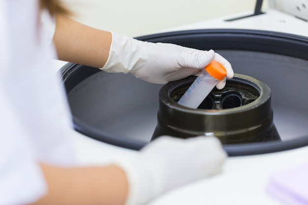 Wetenschapper die reageerbuis in centrifuge zet