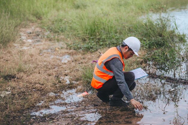 Wetenschapper Ecoloog die een watermonster neemt en de ph-waarde van de rivier afleest Watervervuiling en behoud en beheer van waterconcepten