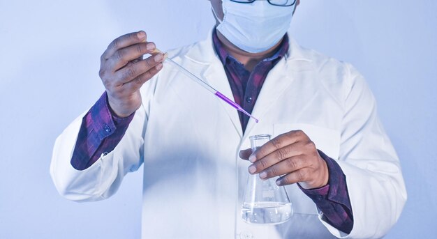 Wetenschapper giet kleurvloeistof in een erlenmeyer met een druppelaar in het scheikundig laboratorium. Wetenschapper die een chemisch experiment uitvoert