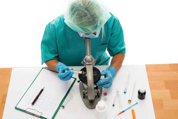 Wetenschapper in blauwe medische handschoenen en uniform lerende COVID-19-monsters met microscoop in laboratorium