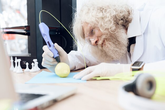 Foto wetenschapper met grijze baard schildert groene appel met 3d-handvat.