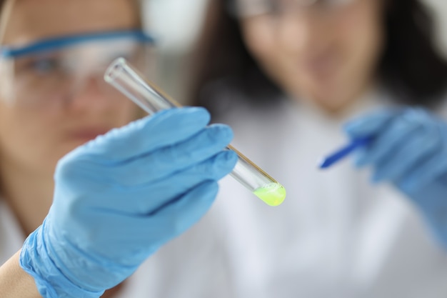 Foto wetenschapper toont reageerbuis met gele stof in chemisch laboratoriumonderzoek van een stof