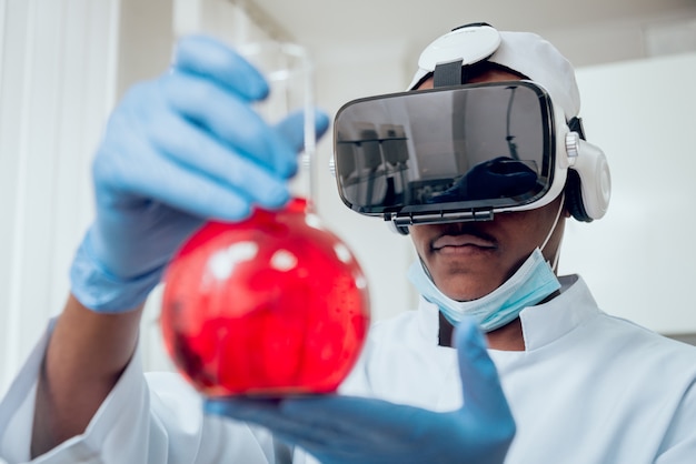 Wetenschapstechnicus in virtual reality-bril onderzoekt het medicijn in laboratorium.