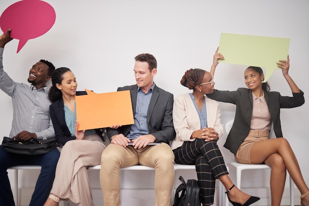 Weve got something to say. Shot of a group of young businesspeople holding speech bubbles while waiting in line.