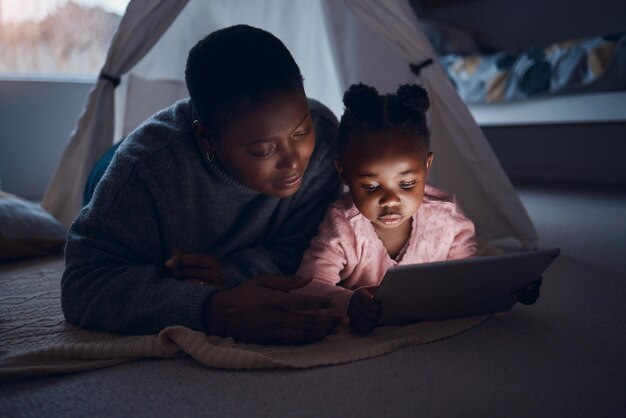 What are you going to read mom Shot of a mother reading bedtime stories with her daughter on a digital tablet