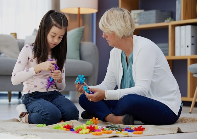 家でおもちゃで遊んでいる女の子と彼女の祖母のショットを何を作っていますか