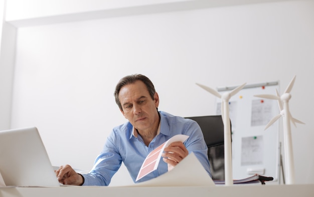 Cosa scegliere. ingegnere professionista seduto in ufficio e lavorando al laptop durante l'elaborazione del progetto di turbine eco