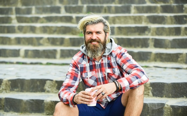 What a great morning. hipster relax on stairs. mature traveler having rest. take away coffee. good morning inspiration. brutal man with beard drinking tea from cup. bearded man drink coffee outdoor.