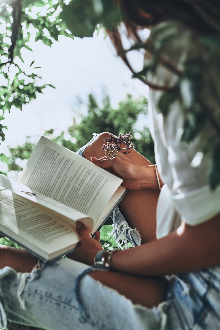 Photo what is going to happen next? close-up of young woman holding an open book while spending time outdoors