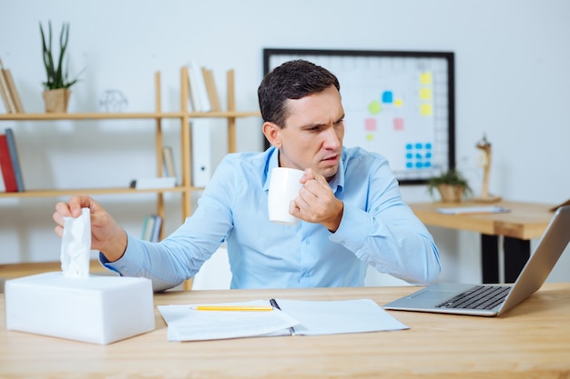 What is going on. Irritated male person opening mouth and taking serviette while drinking tea