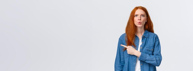 Фото Что это за привлекательная рыжеволосая девушка в джинсовой рубашке смотрит на вопрос, задавая вопрос и указывая на фи?
