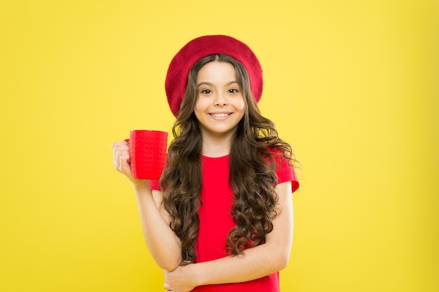 What is your favorite juice Drink enough water Girl kid hold mug yellow background Child hold mug Drinking tea juice cocoa Relaxing with drink Child smiling drink beverage Homebrewed drink