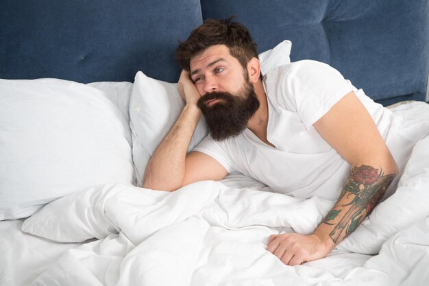 What a long night Sleep disorders concept Man bearded hipster having problems with sleep Guy lying in bed try to relax and fall asleep Relaxation techniques Violations of sleep and wakefulness