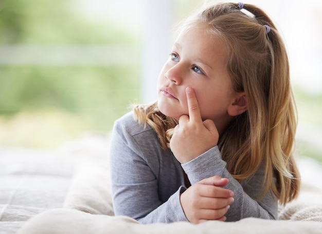 What should I have for lunch. Shot of a young girl relaxing in her bedroom daydreaming.