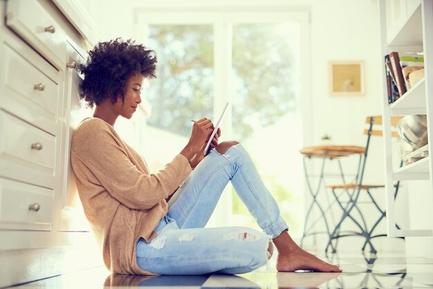 Photo what would the weekend be without some wireless entertainment shot of a young woman using a digital tablet at home