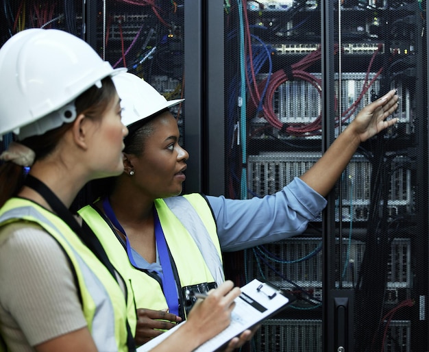 What do you see Cropped shot of two attractive female programmers working in a server room