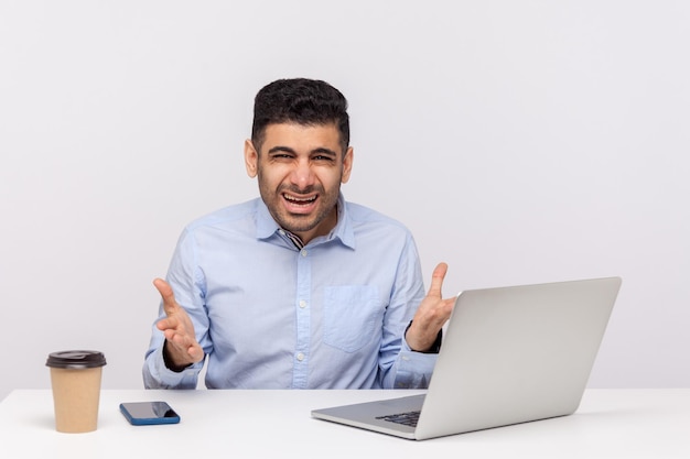 What do you want Annoyed businessman angry boss sitting in office raising hands indignant irritated looking at camera misunderstanding at work indoor studio shot isolated on white background