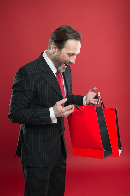 Whats in bags. Happy director look into colorful bags. Mature man hold shopping bags. Sale and discount. Business gifts preparation. Holiday purchases in paper bags. Reuse and recycle.