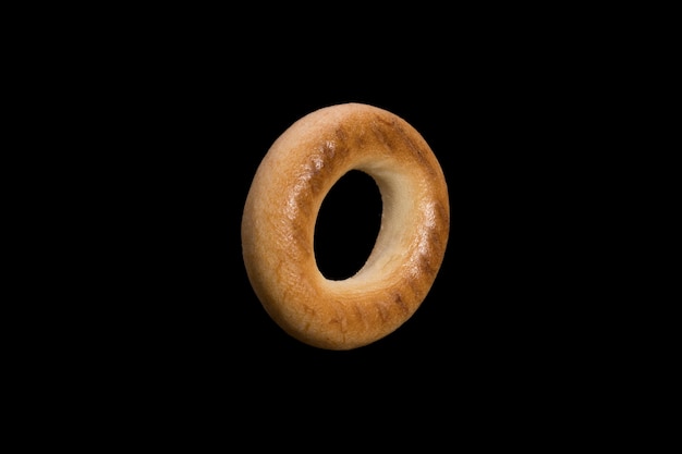 Pane di pasta choux di grano a forma di anello. bagel isolato su sfondo nero. foto di alta qualità