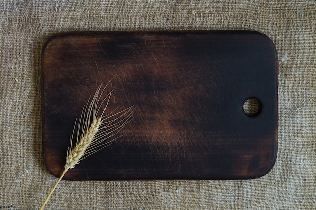 Wheat ear on a kitchen board on a sacking background. Top view