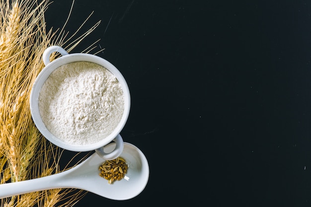 Wheat ears and flour on black 