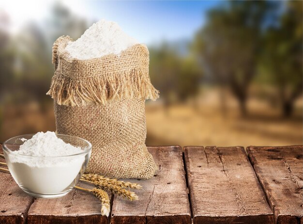 Wheat ears and flour on wooden background