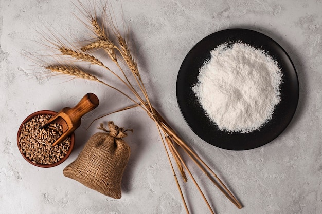 Wheat ears, wheat grains, and wheat flour on the kitchen table.