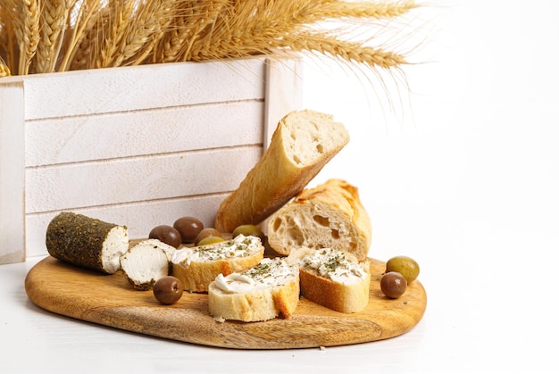 Wheat ears in a white wooden box bread cottage cheese and olives