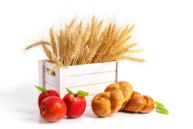 Колосья пшеницы в белой деревянной коробке красные яблоки и хлеб Концепция израильского праздника Шавуот