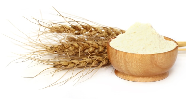 Wheat and flour on a bowl over white background