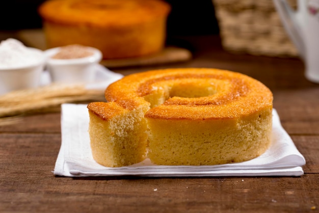 Wheat flour cake and slice on wood with other cake in the background with wheat branch beside.