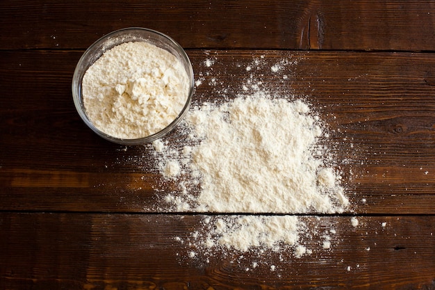 Photo wheat flour for preparing bakery products in glass bowl on the wooden table