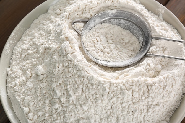 Wheat flour and sieve in bowl closeup
