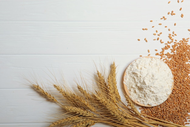 Wheat flour and spikelets of wheat on a light background