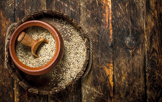 Wheat grain in a bowl with a scoop on a wooden background